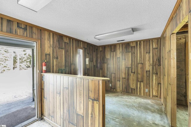 bar featuring wooden walls, a textured ceiling, and visible vents