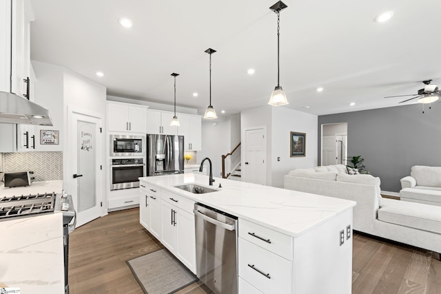 kitchen with appliances with stainless steel finishes, tasteful backsplash, a sink, open floor plan, and recessed lighting