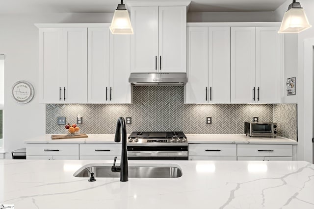kitchen with a sink, gas range, white cabinetry, a toaster, and under cabinet range hood