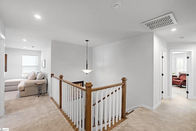 hall with carpet flooring, a healthy amount of sunlight, and an upstairs landing
