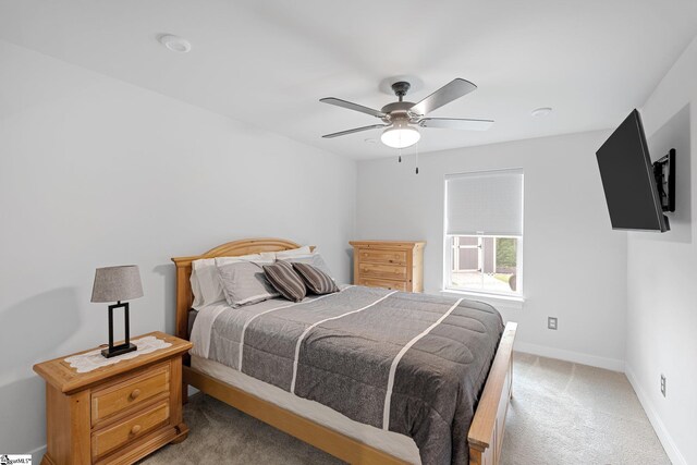 bedroom with baseboards, light carpet, a ceiling fan, and cooling unit