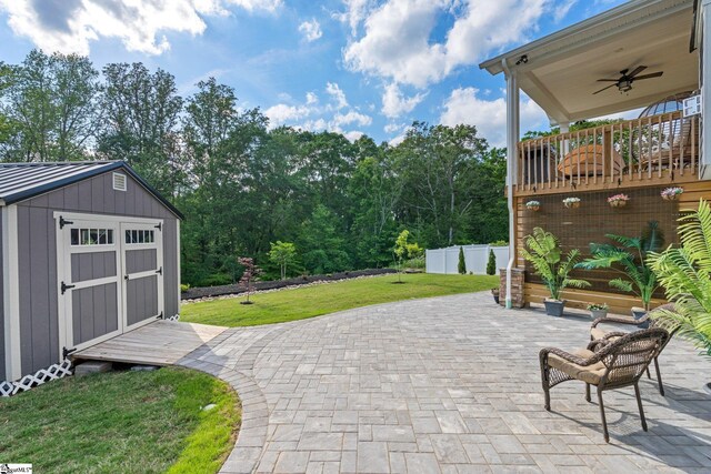 view of patio / terrace featuring an outbuilding, a ceiling fan, fence, and a storage shed