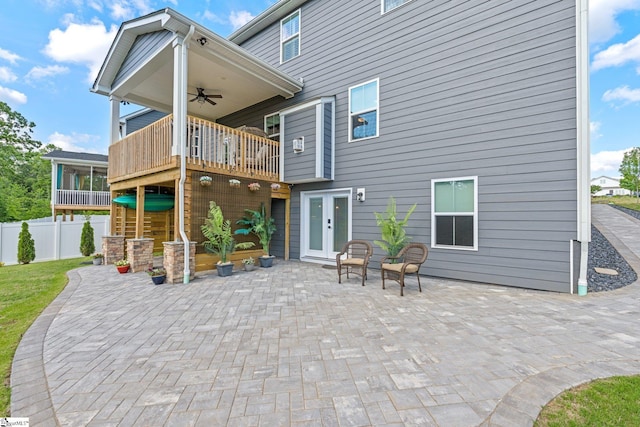 back of property with french doors, a ceiling fan, a patio area, fence, and a balcony