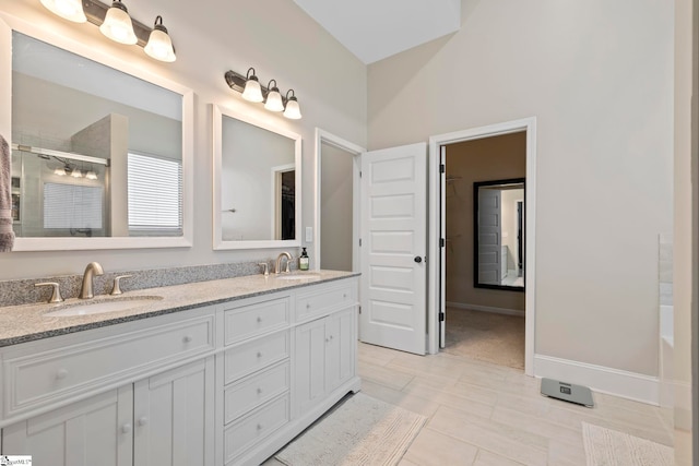 full bathroom with double vanity, a sink, and a stall shower