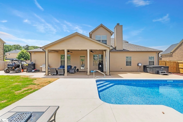 rear view of house featuring fence, a patio, a chimney, a ceiling fan, and a hot tub