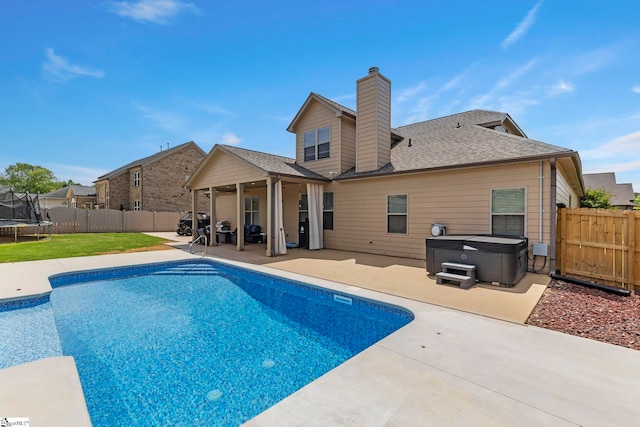 view of swimming pool with a hot tub, a patio, a fenced backyard, and a trampoline