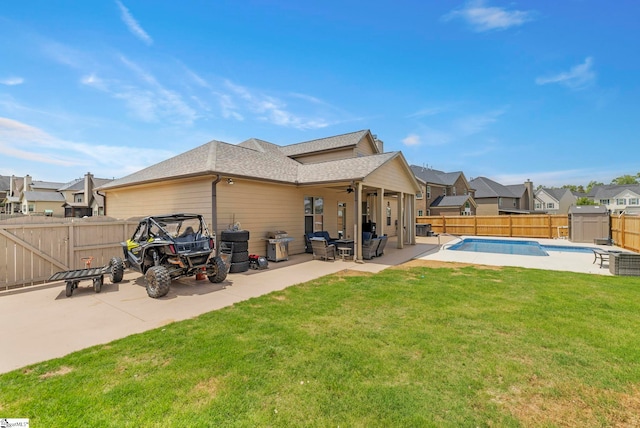 rear view of property with a fenced in pool, a fenced backyard, a patio area, a lawn, and a ceiling fan