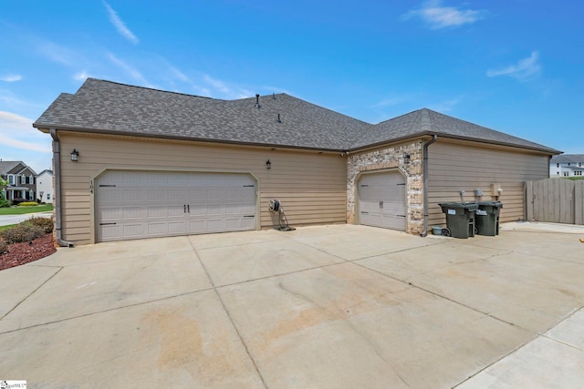 view of front facade featuring fence, a shingled roof, an attached garage, and driveway