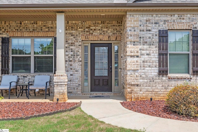 doorway to property with a porch and brick siding