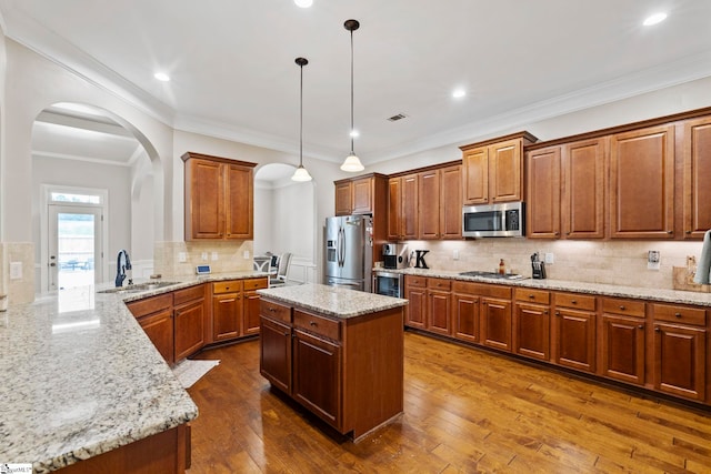 kitchen featuring decorative backsplash, light stone countertops, arched walkways, a sink, and stainless steel appliances