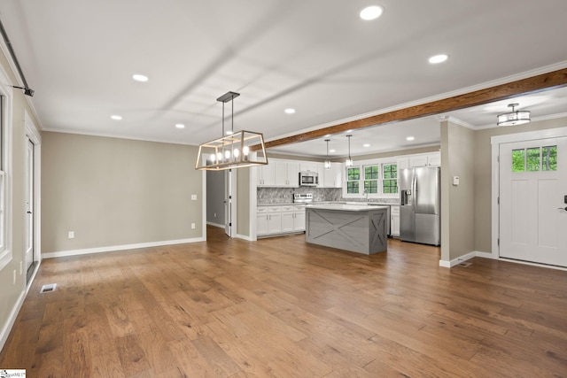 kitchen with crown molding, recessed lighting, a center island, appliances with stainless steel finishes, and backsplash