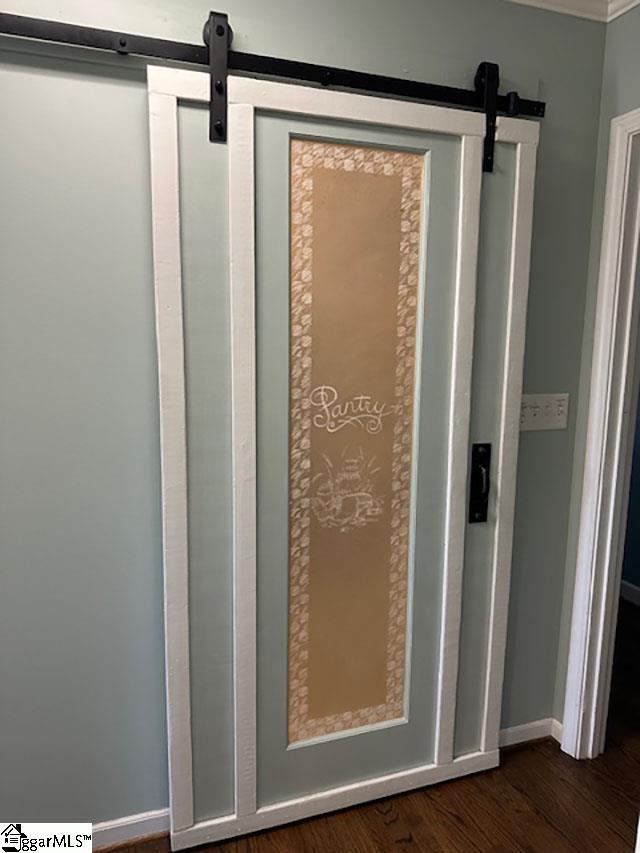 details featuring baseboards, a barn door, and wood finished floors