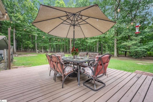 wooden deck featuring a lawn, fence, and outdoor dining space