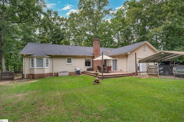 rear view of property with a chimney, roof with shingles, a deck, a carport, and a yard