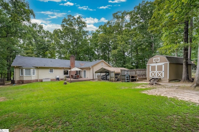 back of house featuring a storage unit, an outdoor structure, a lawn, and a deck