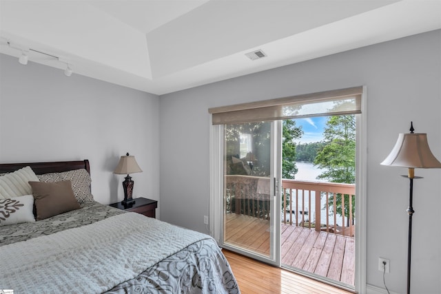 bedroom with visible vents, track lighting, wood finished floors, and access to exterior