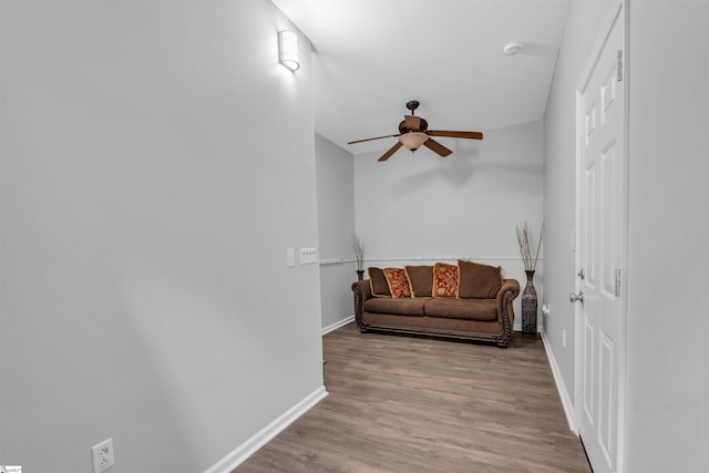 living area with baseboards, ceiling fan, and wood finished floors