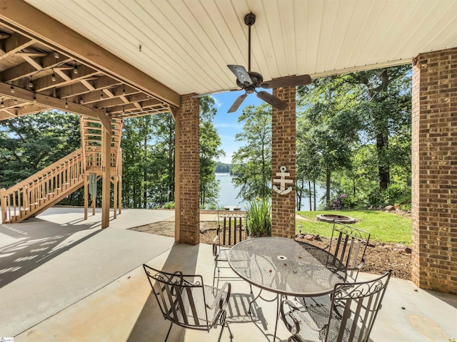 view of patio featuring stairs, a water view, a ceiling fan, and outdoor dining space