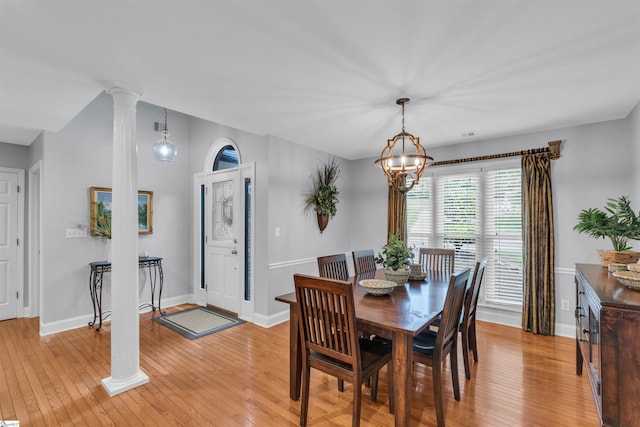 dining area with baseboards, decorative columns, light wood finished floors, and a chandelier