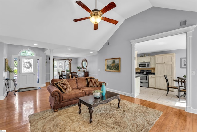 living area with a ceiling fan, decorative columns, light wood finished floors, and visible vents