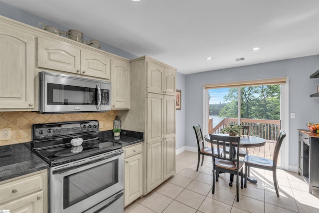 kitchen with stainless steel appliances, baseboards, decorative backsplash, cream cabinetry, and visible vents