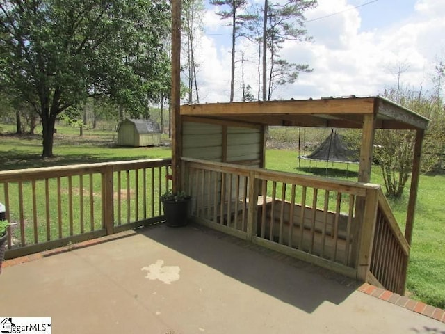 deck featuring a storage unit, a trampoline, an outdoor structure, and a yard