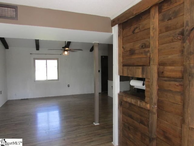 unfurnished living room with a ceiling fan, beam ceiling, visible vents, and wood finished floors
