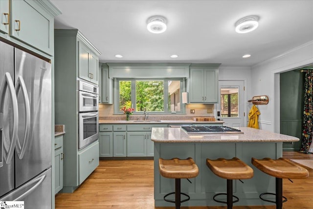 kitchen with crown molding, a breakfast bar, tasteful backsplash, a sink, and stainless steel appliances