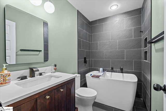bathroom with a freestanding tub, tile walls, vanity, tile patterned floors, and toilet