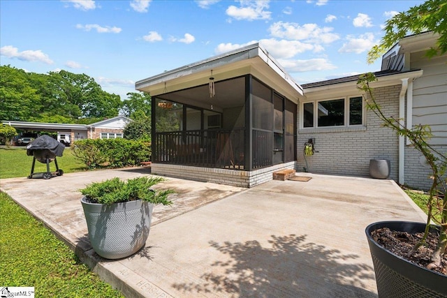 rear view of property with a sunroom, a patio area, and brick siding
