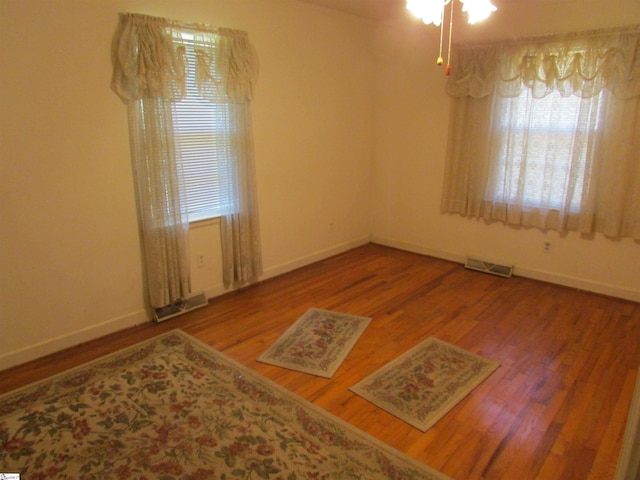 unfurnished room featuring baseboards, wood finished floors, and visible vents