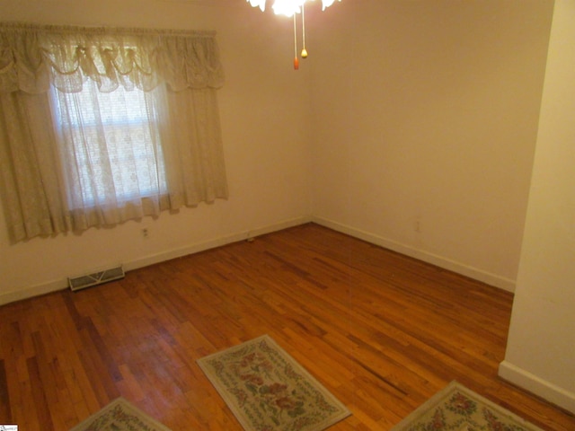 empty room featuring baseboards, a ceiling fan, wood finished floors, and visible vents
