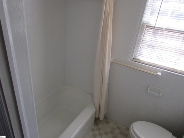 full bath featuring toilet, tile patterned floors, tile walls, and shower / bath combo with shower curtain