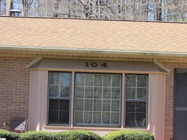 exterior details featuring brick siding and a shingled roof