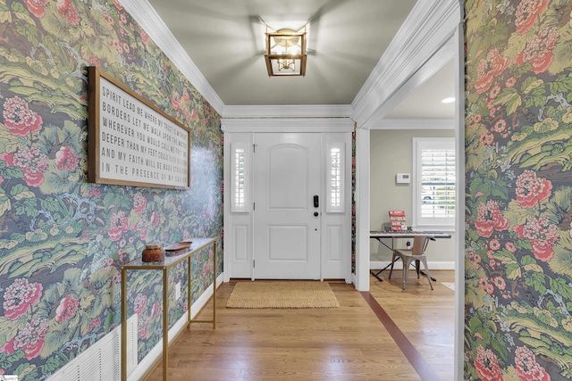 foyer entrance with baseboards, ornamental molding, wood finished floors, and wallpapered walls