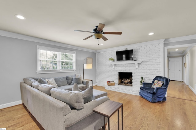 living area with crown molding, light wood-style floors, a fireplace, and a ceiling fan