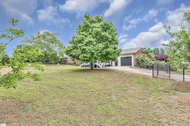 view of yard featuring fence, driveway, and a garage