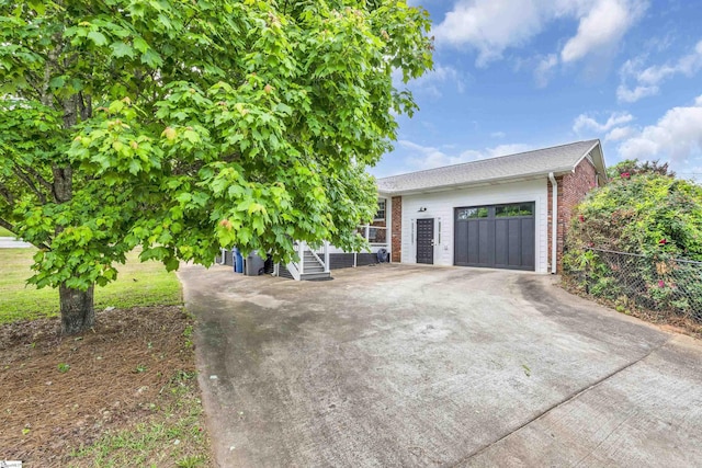 garage with concrete driveway and fence