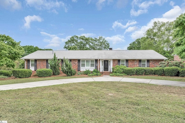 ranch-style house featuring roof with shingles, curved driveway, a front lawn, and brick siding