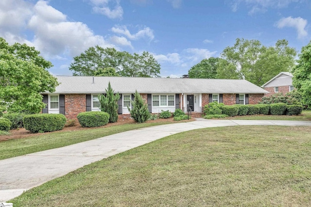 ranch-style home featuring brick siding, a shingled roof, and a front yard