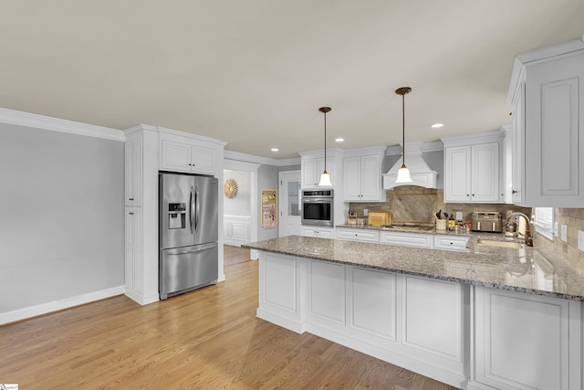 kitchen with a peninsula, custom range hood, a sink, appliances with stainless steel finishes, and backsplash