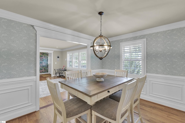 dining area featuring wallpapered walls, an inviting chandelier, and a wainscoted wall