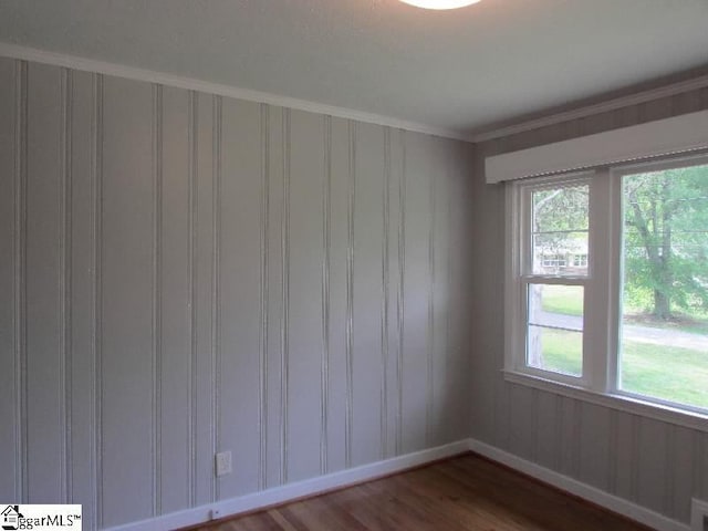 unfurnished room featuring crown molding, baseboards, and wood finished floors