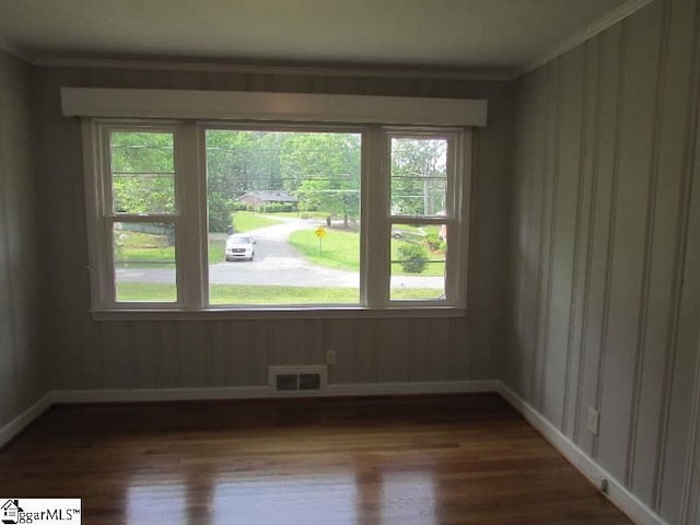 unfurnished room with baseboards, a wealth of natural light, dark wood-style floors, and visible vents
