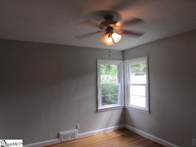 empty room featuring visible vents, a ceiling fan, a wealth of natural light, and light wood-type flooring