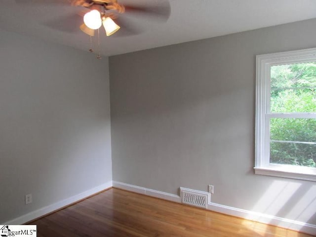 spare room featuring baseboards, ceiling fan, visible vents, and wood finished floors