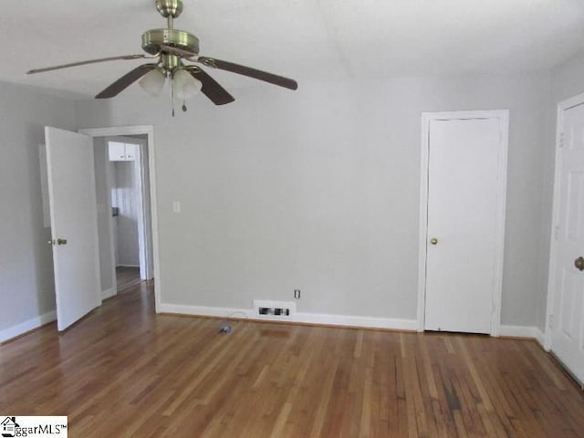 spare room featuring visible vents, baseboards, ceiling fan, and wood finished floors