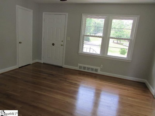 unfurnished room featuring baseboards, visible vents, and wood finished floors