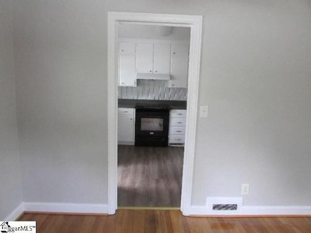 hallway with visible vents, baseboards, and wood finished floors