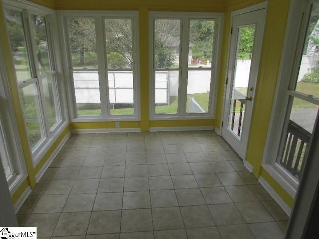 unfurnished sunroom featuring baseboards, tile patterned flooring, french doors, and a wealth of natural light